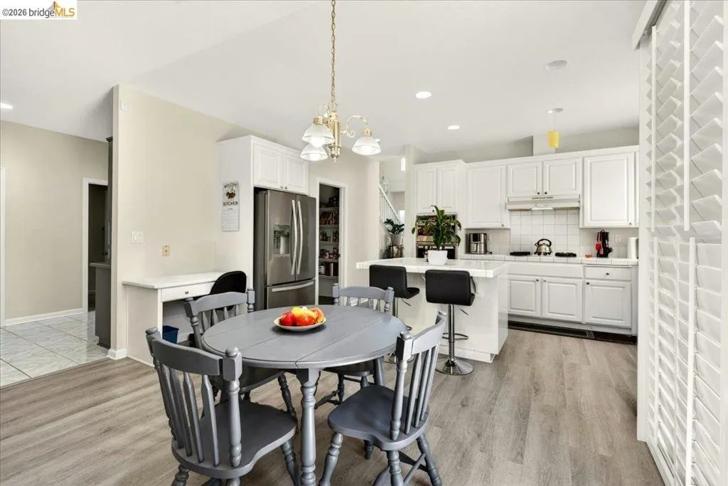 Open-concept kitchen featuring white cabinetry, stainless steel refrigerator, and a kitchen island with seating