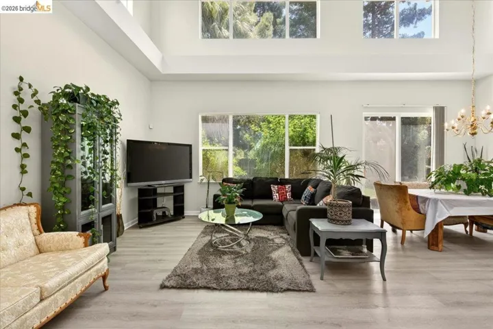 Spacious living area featuring light-toned flooring, high ceilings, and abundant natural light from multiple windows
