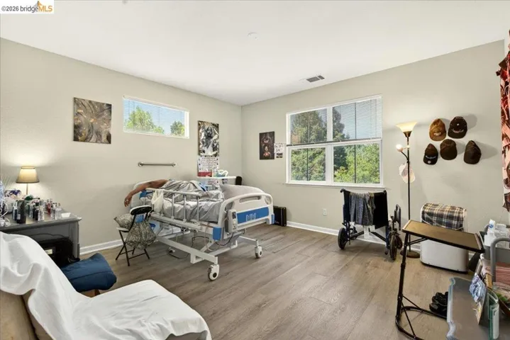 Spacious room featuring wood-finish flooring, light-toned walls, and multiple windows