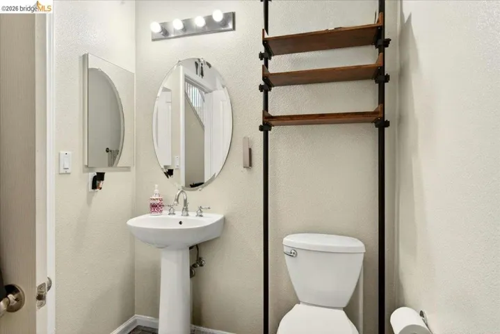 Pedestal sink with chrome faucet, an oval mirror, and a wall-mounted medicine cabinet