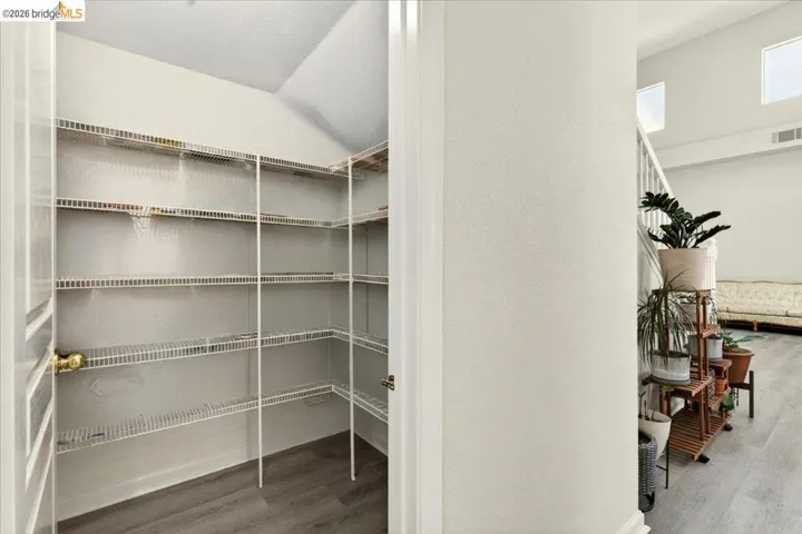 Walk-in pantry featuring extensive wire shelving, wood-finish flooring, and light-toned wall finishes