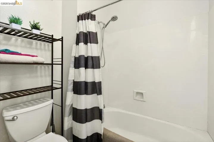 White bathtub and shower combination with a wall-mounted shower head and built-in soap dish