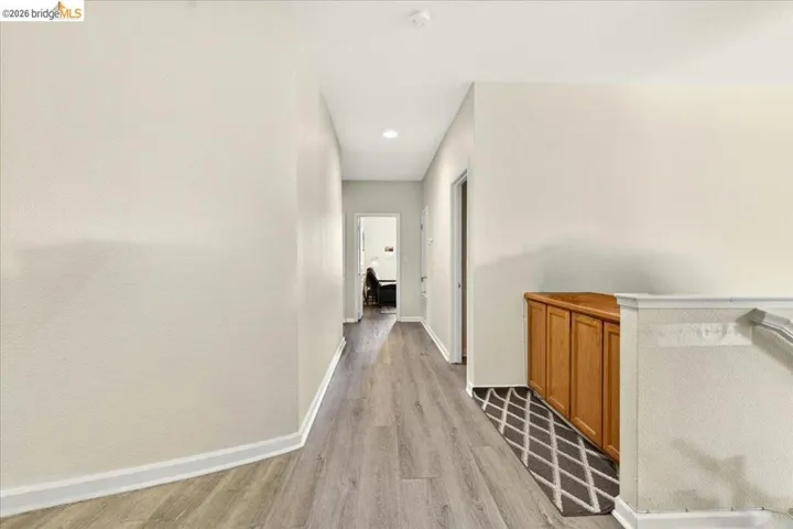Hallway featuring wood-finish flooring, light-toned walls, recessed lighting, and white baseboards