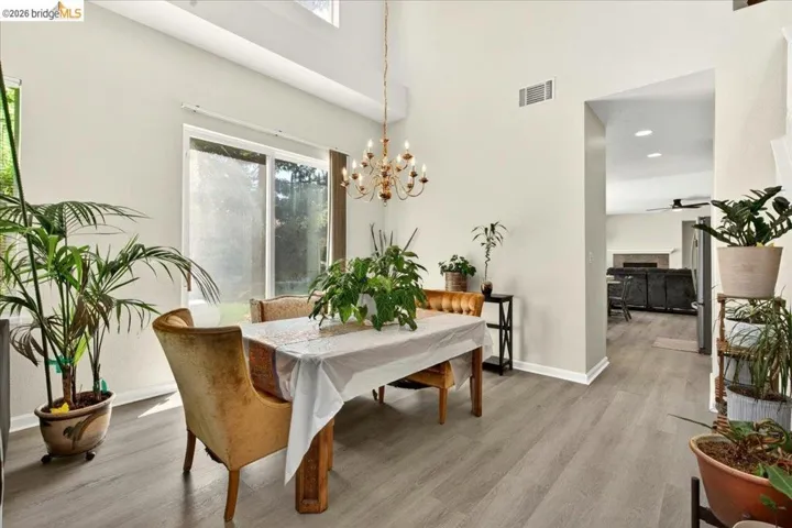 Dining area featuring vaulted ceilings, skylights, chandelier lighting, wood-finish flooring, and sliding glass door access to the exterior