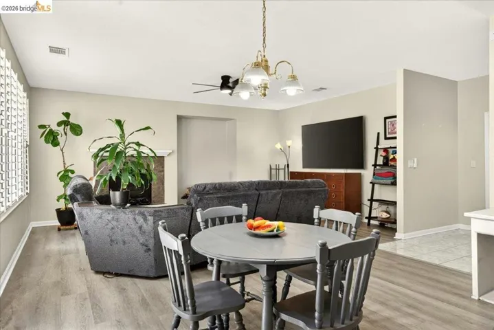 Open concept living space featuring a fireplace, wood-finish flooring, and a ceiling fan