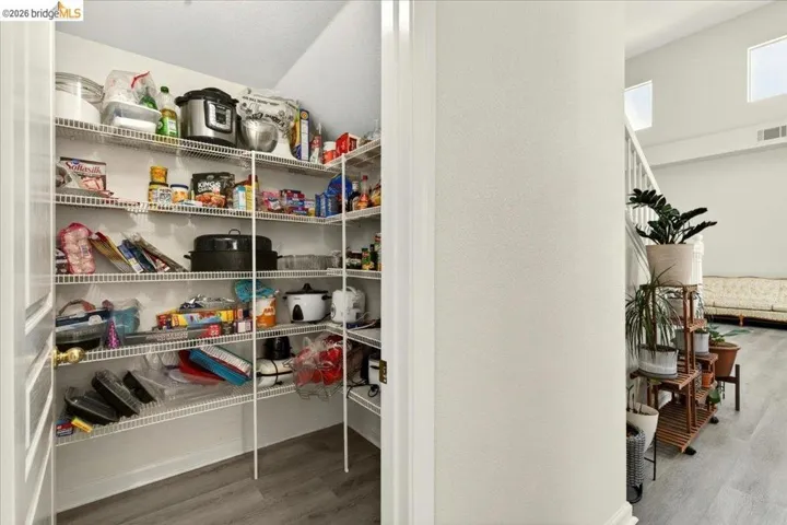 Walk-in pantry featuring wire shelving and wood-finish flooring