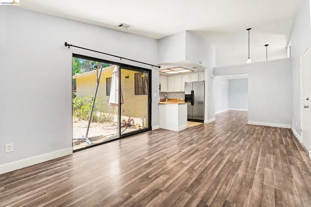 Spacious living area featuring wood-finish flooring, light grey walls, and a sliding glass door