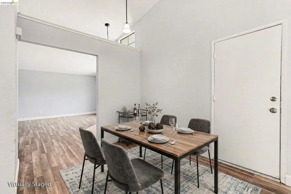 Vaulted ceiling with high windows, wood-finish flooring, recessed lighting, and a neutral color palette throughout