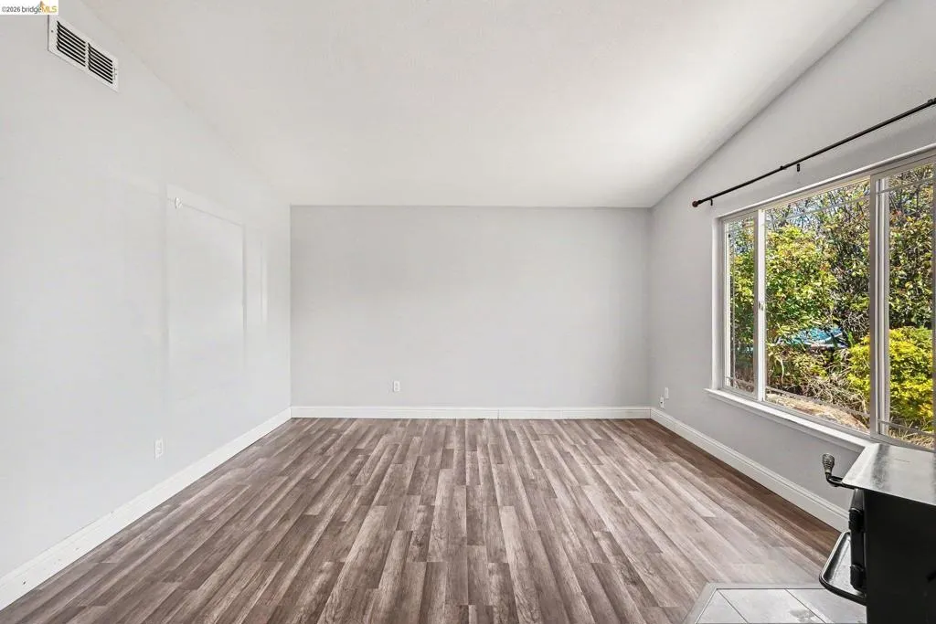Spacious interior with wood-finish flooring, vaulted ceiling, and white baseboards