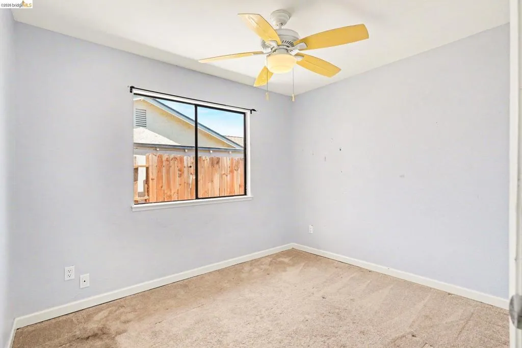 Room featuring neutral wall paint, a window with black trim, and a ceiling fan with light kit