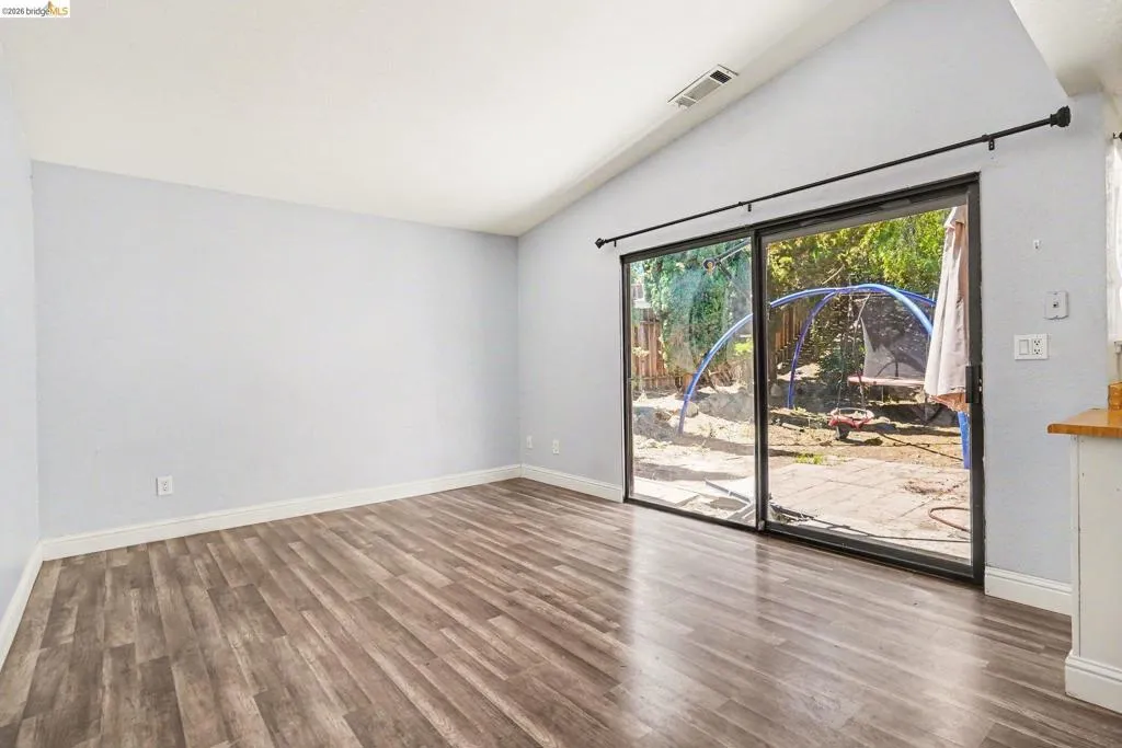 Spacious interior featuring wood-finish flooring, a vaulted ceiling, and light-toned walls