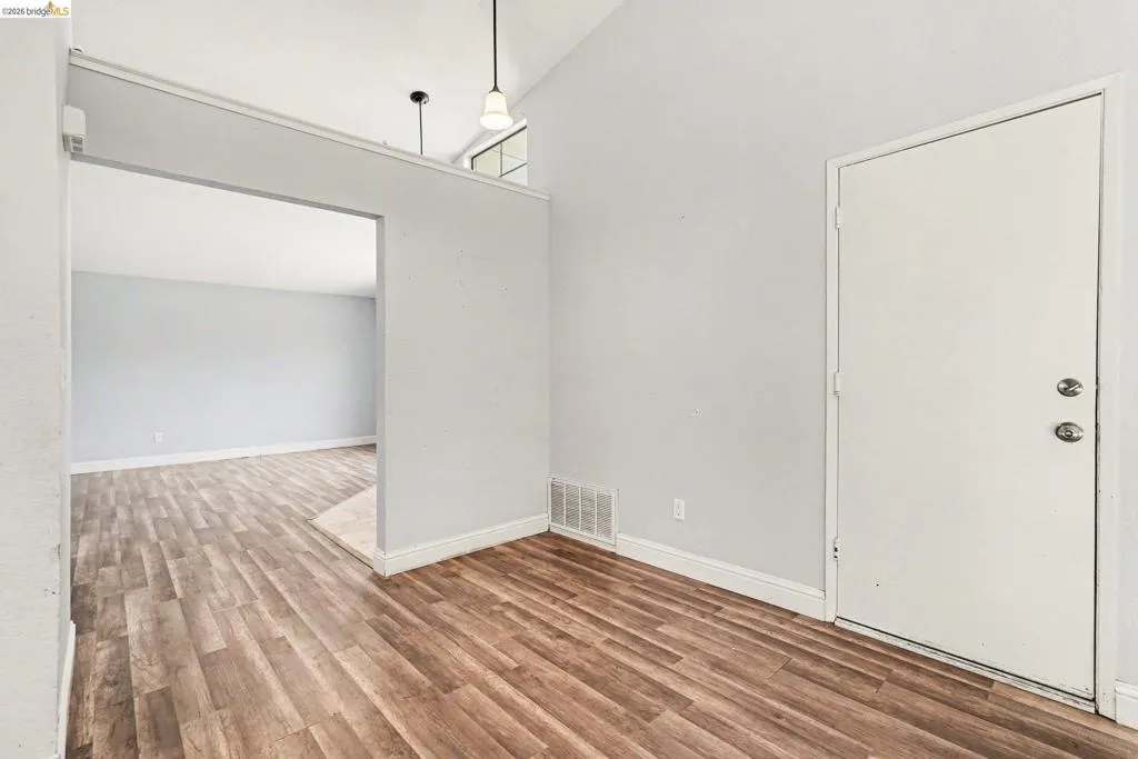 Entry area featuring wood-finish flooring, a vaulted ceiling, and an arched doorway leading to an additional space