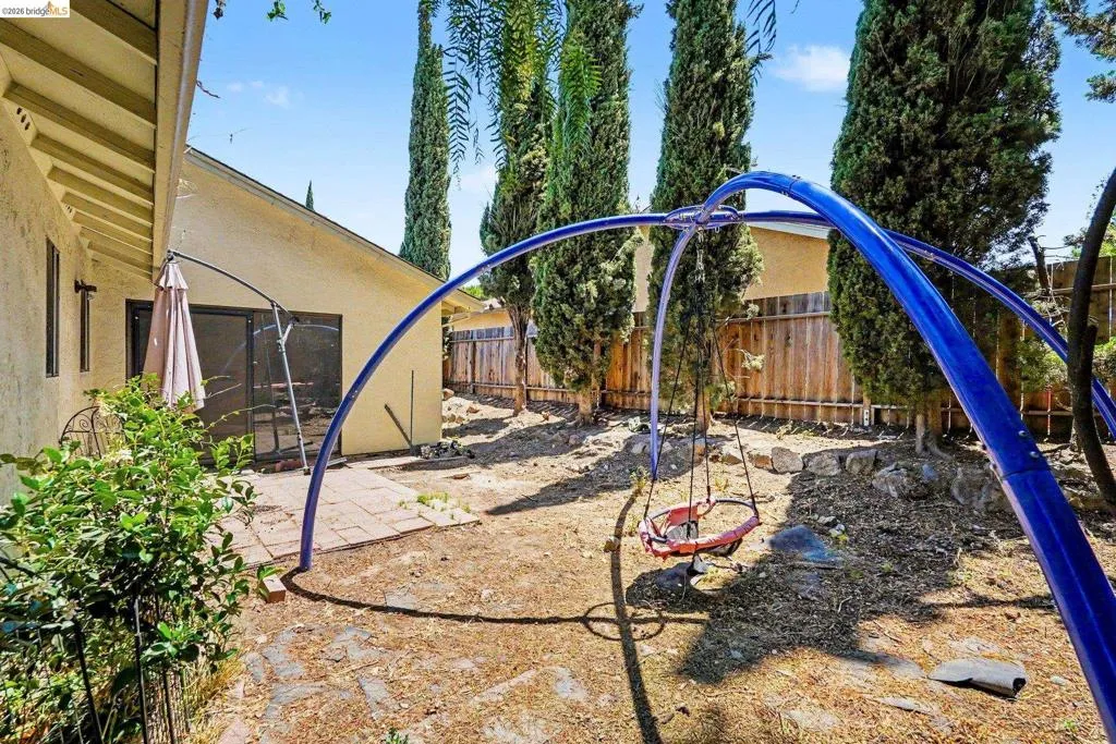 Private backyard featuring a paved patio area, mature trees, and a privacy fence