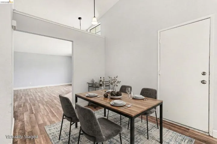 Vaulted ceiling with high windows, wood-finish flooring, recessed lighting, and a neutral color palette throughout