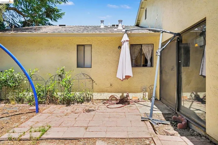 Exterior stucco wall with two windows and a sliding glass door