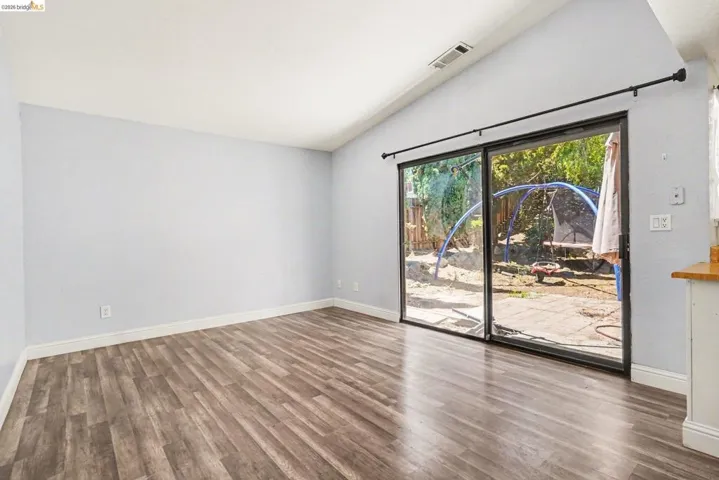 Spacious interior featuring wood-finish flooring, a vaulted ceiling, and light-toned walls