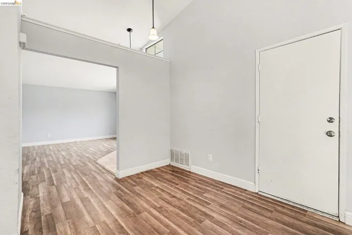 Entry area featuring wood-finish flooring, a vaulted ceiling, and an arched doorway leading to an additional space