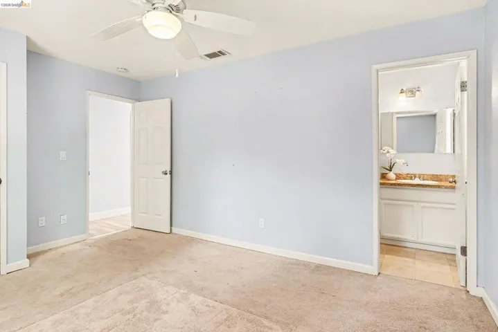 Carpeted room featuring a ceiling fan with integrated lighting, light blue walls, and white trim