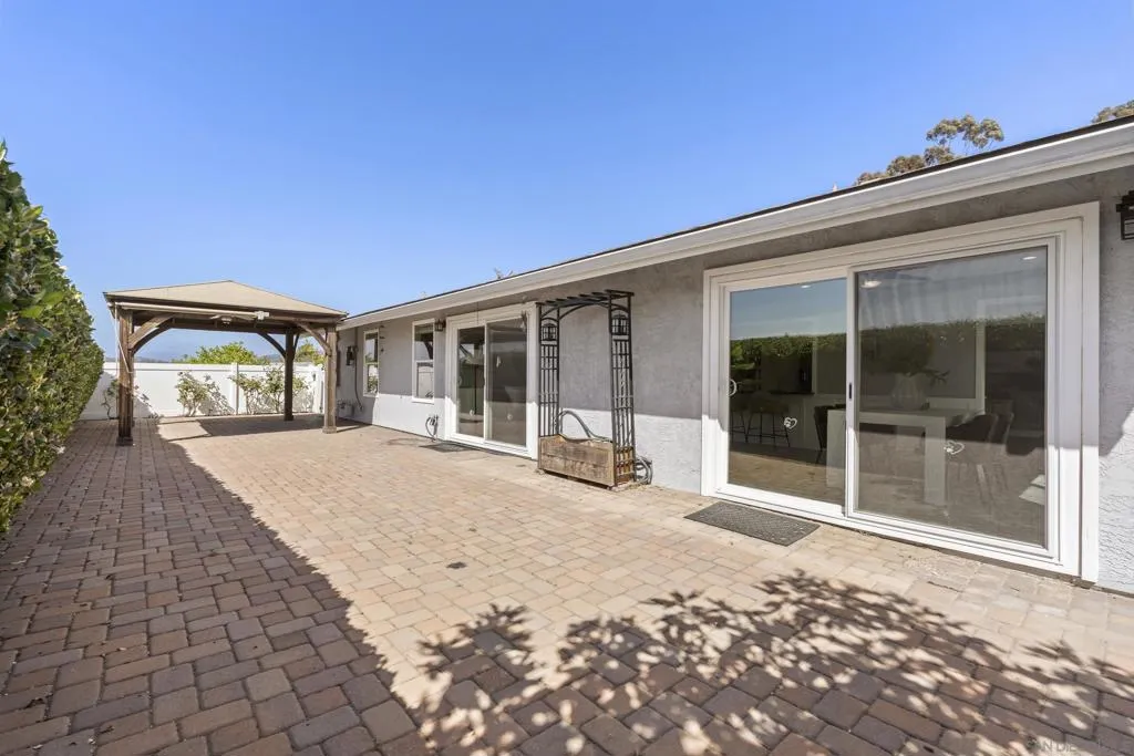 Beautifully laid brick patio with pergola and ceiling fan inside pergola