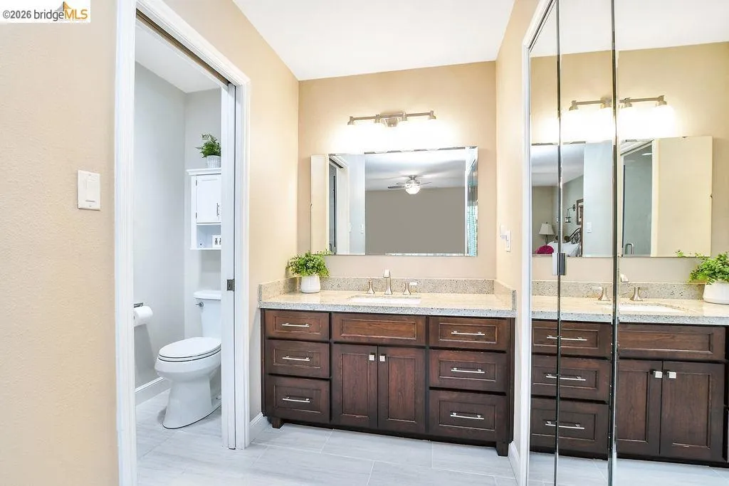 Dual vanity with wood-finish cabinetry, light-toned countertop, and undermount sinks