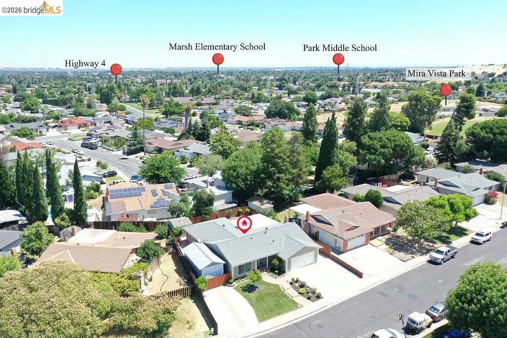Aerial perspective showcasing a residential neighborhood with a single-story home featuring a grey roof and an attached garage