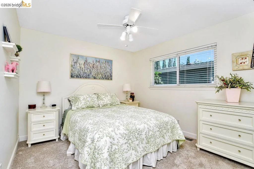 Bedroom featuring neutral-toned carpet, a window with horizontal blinds, and a ceiling fan with integrated lighting