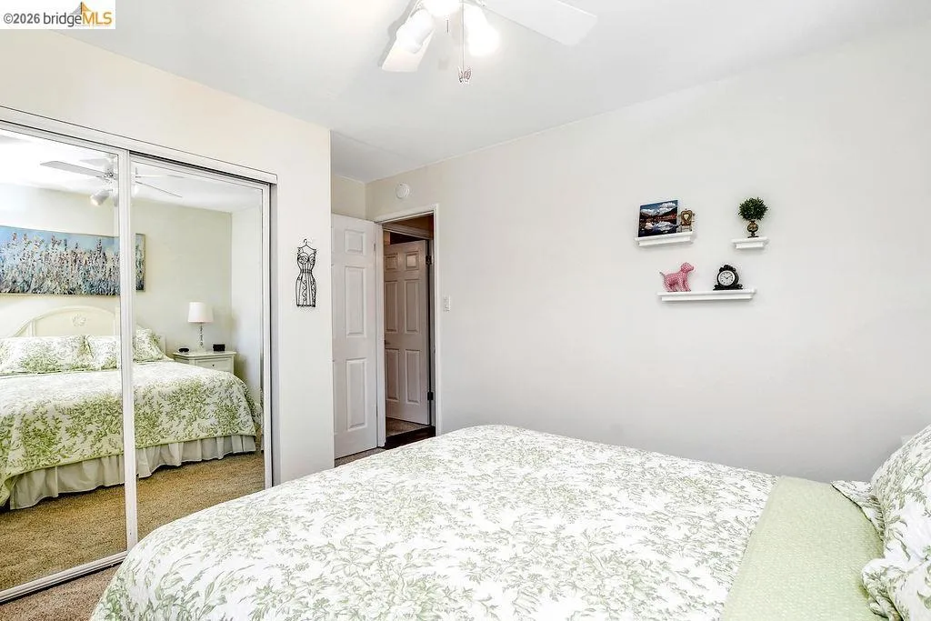 Bedroom featuring mirrored closet doors, a ceiling fan with light fixture, and neutral wall paint