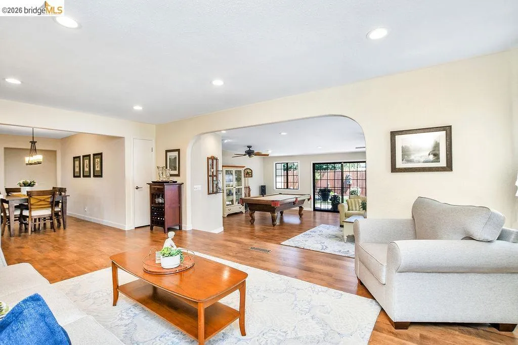Spacious interior featuring wood-finish flooring throughout, recessed ceiling lighting, and a broad arched entryway