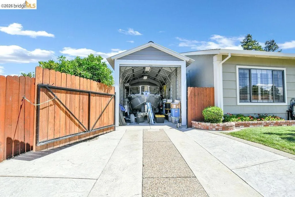 Expansive concrete driveway leading to a sheltered carport structure
