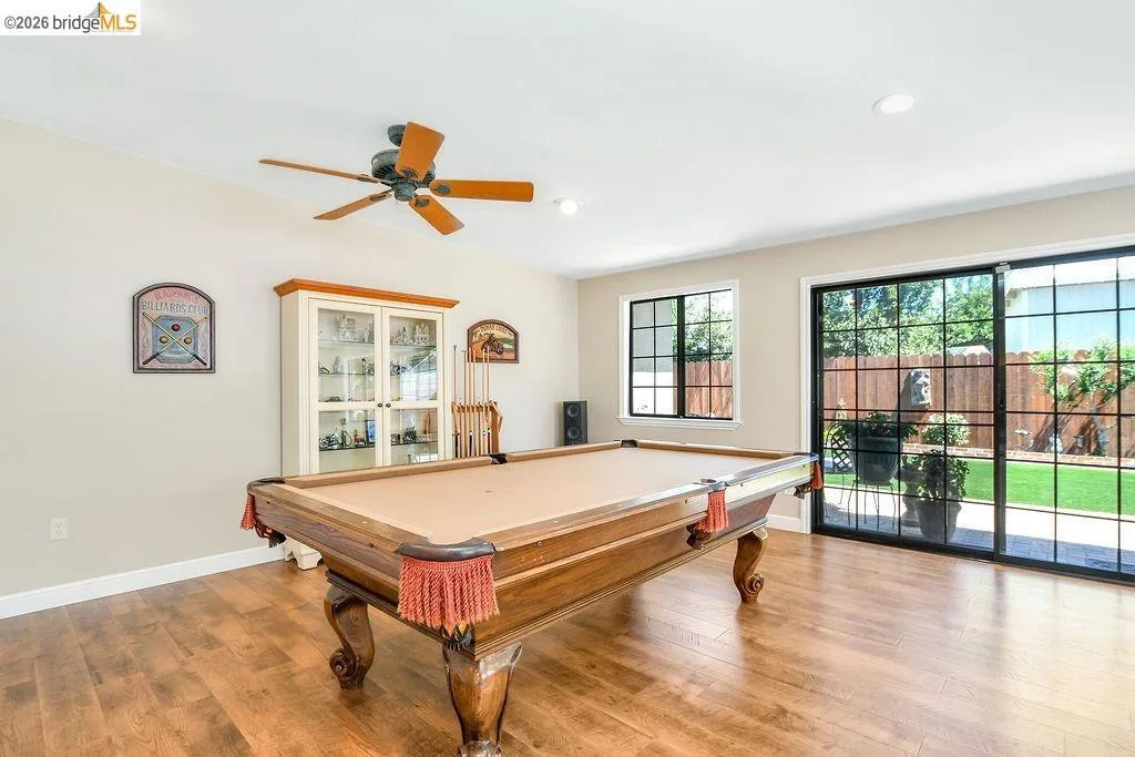 Spacious interior featuring wood-finish flooring, a ceiling fan, recessed lighting, and a display cabinet with glass doors