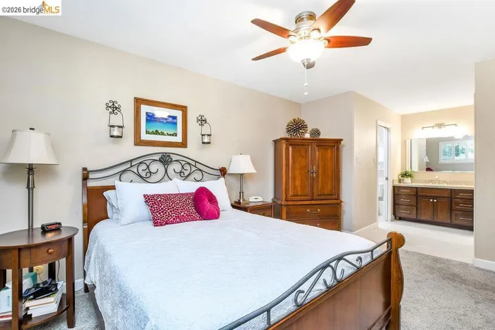Carpeted room with a ceiling fan light fixture and a wood-finish bed frame