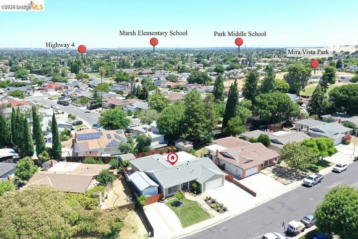 Aerial perspective showcasing a residential neighborhood with a single-story home featuring a grey roof and an attached garage