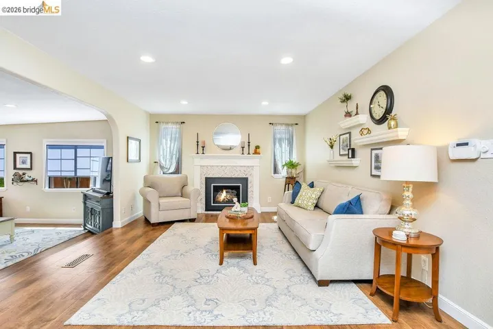 Living room featuring wood-finish flooring, recessed lighting, and a fireplace with a tiled surround