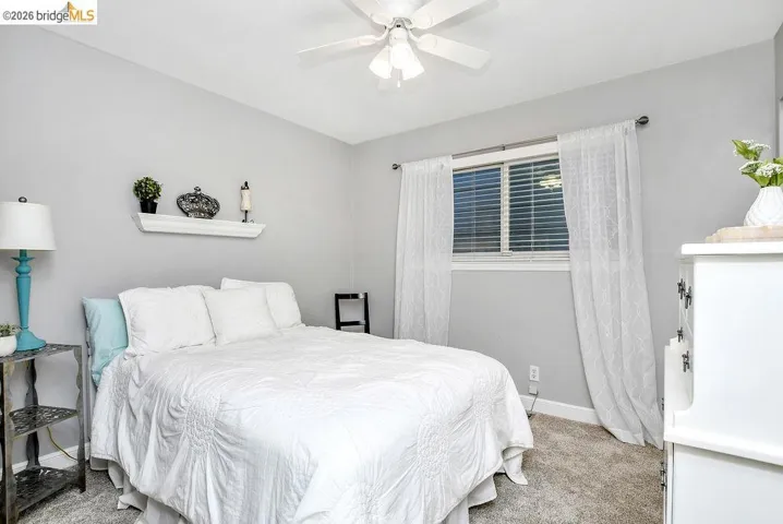 Bedroom featuring neutral-toned walls, carpet flooring, and a ceiling fan with integrated lighting