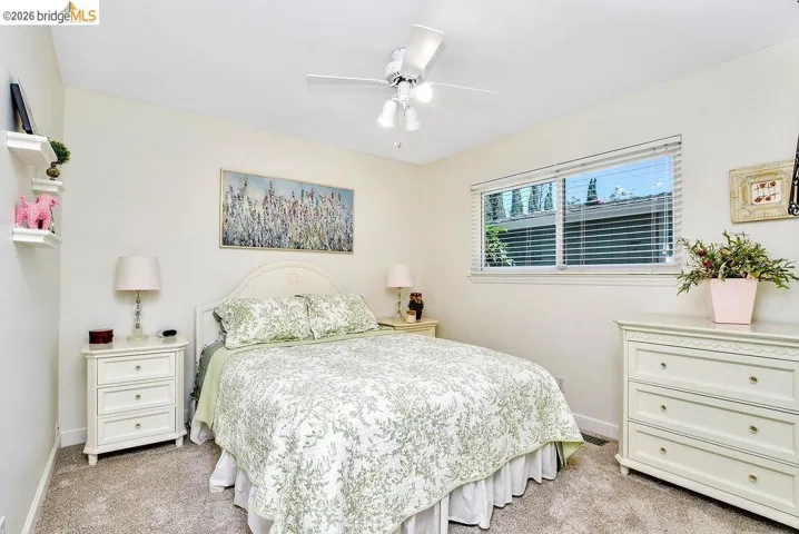 Bedroom featuring neutral-toned carpet, a window with horizontal blinds, and a ceiling fan with integrated lighting