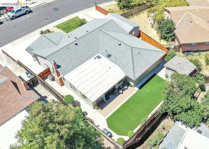 Expansive backyard featuring a rectangular artificial turf lawn, a paved patio area, and perimeter fencing