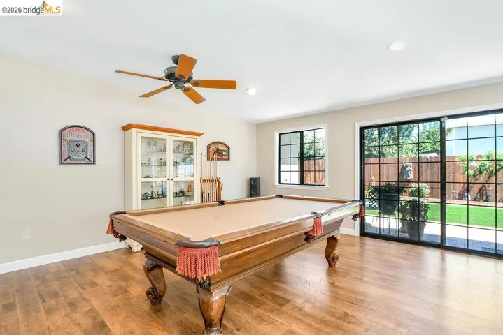 Spacious interior featuring wood-finish flooring, a ceiling fan, recessed lighting, and a display cabinet with glass doors