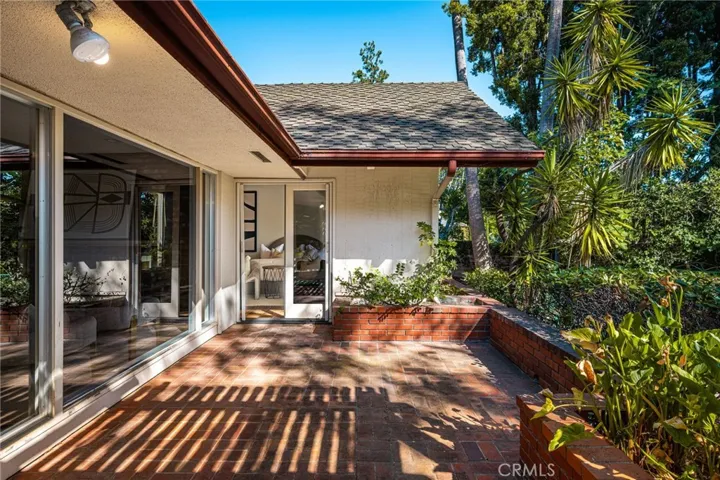 French doors from the primary suite open to the brick patio and pool.