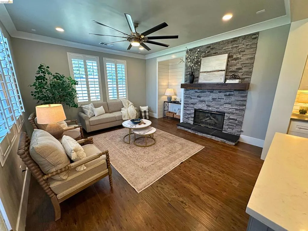 Living area featuring rich wood-finish flooring and a stone-clad fireplace with a substantial wood mantel