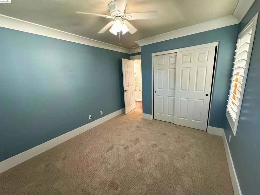 Room featuring crown molding, neutral carpeting, and a ceiling fan with integrated lighting