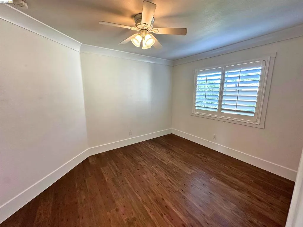 Bright room with wood-finish flooring, white walls, and crown molding