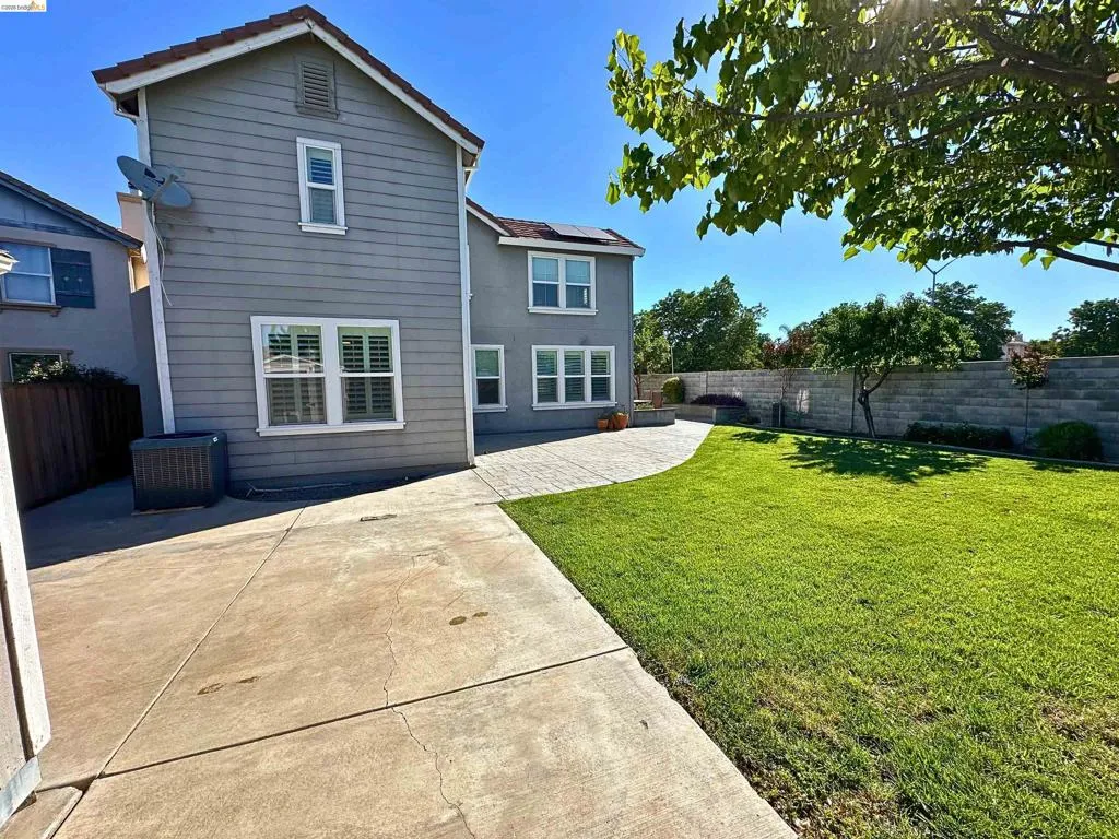 Rear exterior featuring a paver patio and a lawn area