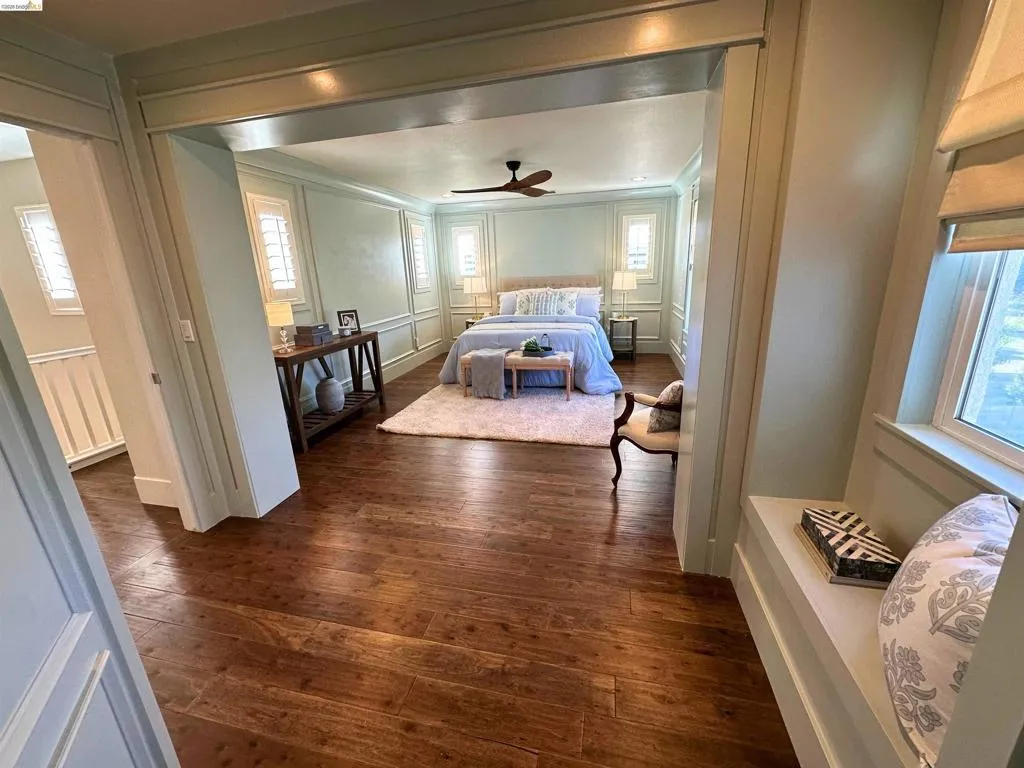 Spacious room featuring rich wood-finish flooring, an arched entryway, and integrated window seating