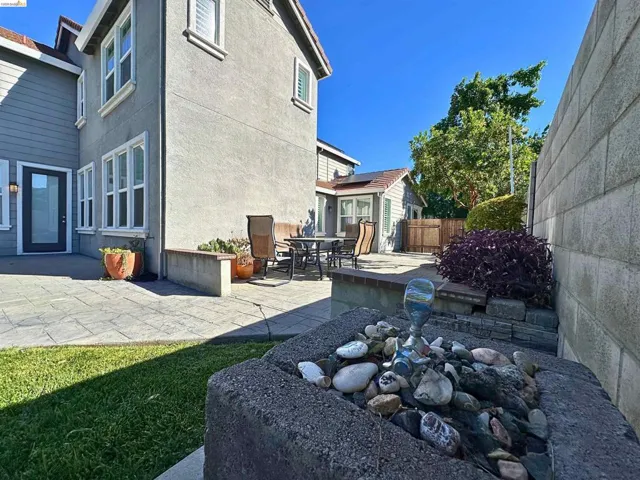 Private patio with pavers, a built-in planter, and a stone water feature