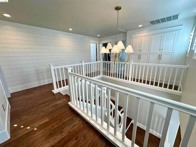 Staircase and upper landing featuring wood-finish flooring, white shiplap accent wall, white balustrade, recessed lighting, and a brass-tone chandelier