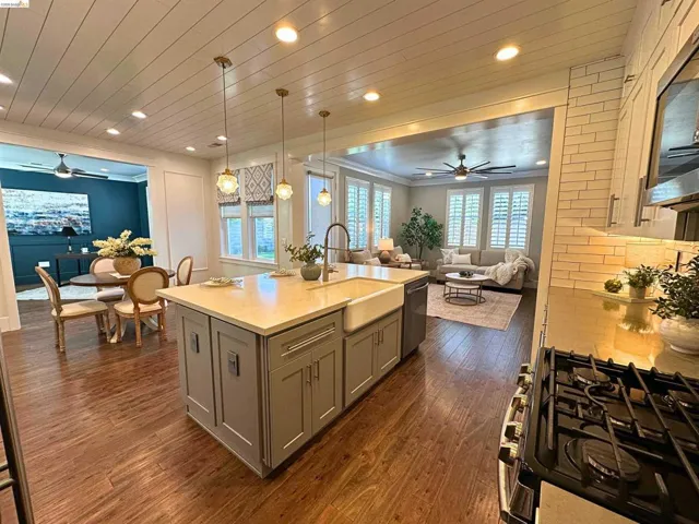 Kitchen featuring a central island with an integrated farmhouse sink, pendant lighting, and light-toned countertops