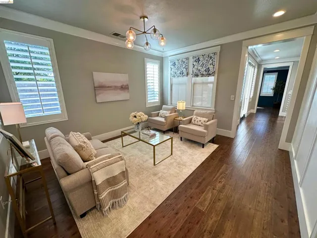 Spacious room featuring wood-finish flooring, white crown molding, and plantation shutters on multiple windows