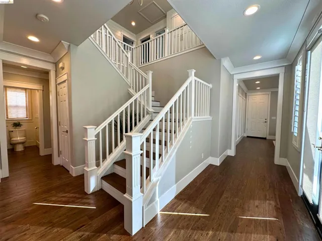 Grand entryway featuring a double staircase with white balusters and dark wood-finish treads