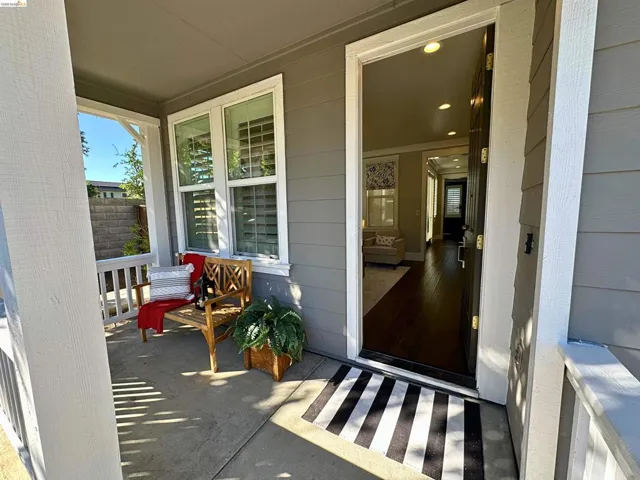 Inviting covered front porch with white railing and gray siding