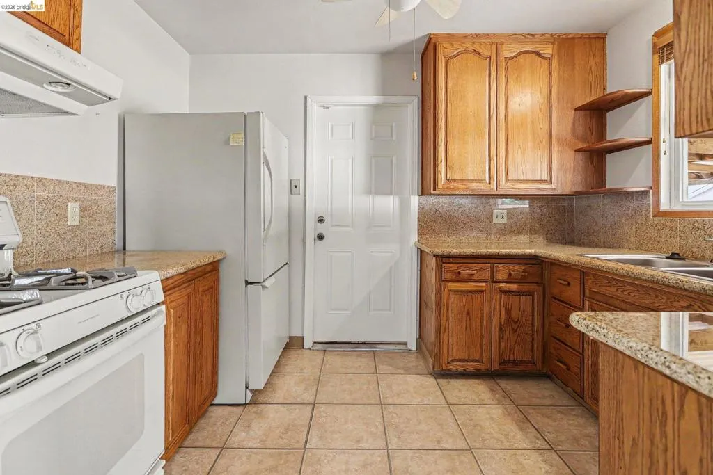 Kitchen featuring wood cabinetry, granite-look countertops, a tile backsplash, and tile flooring